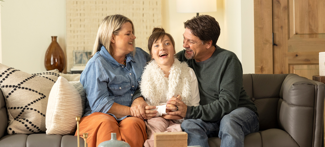 Lucy smiling in between both of her parents on a couch.